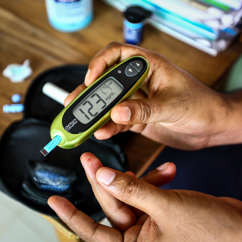 Mains d'un homme tenant un appareil de mesure de la glycémie.