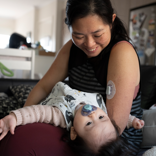 Femme asiatique tenant un enfant en bas âge et souriant.