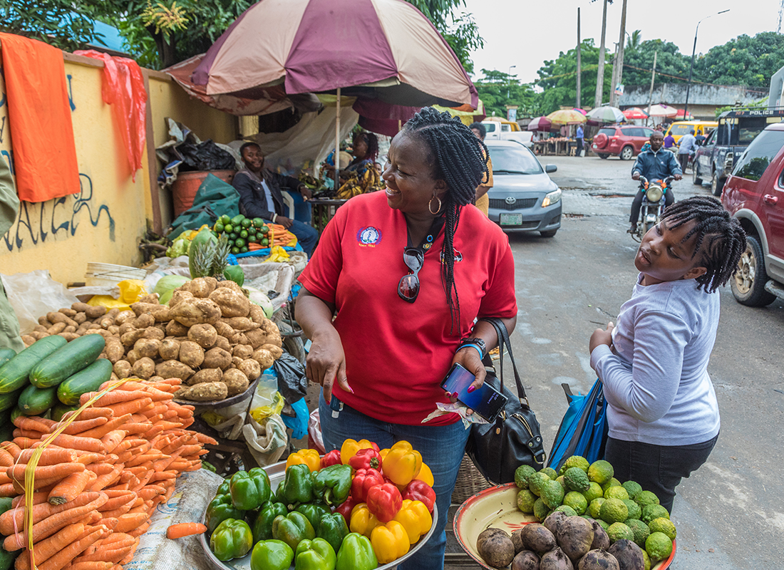 Mujer nigeriana en un puesto de verduras