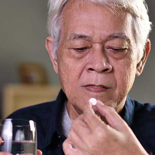 Elderly man about to take a pill with glass of water
