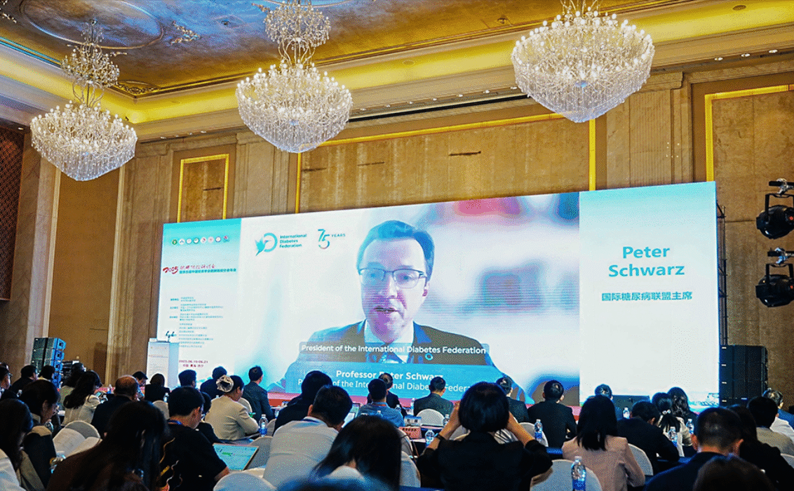 Professor Peter Schwarz, President of the International Diabetes Federation, delivers a virtual keynote address on global diabetes and obesity prevention at the 2025 Obesity Prevention and Control Conference in Xining, China. The high-level event brought together global health experts to advance strategies against rising type 2 diabetes and obesity rates. The image shows Professor Schwarz speaking via live video to an engaged international audience inside a grand conference hall.