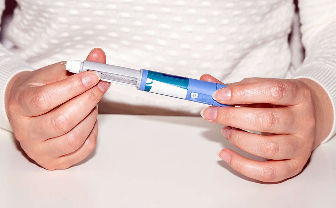 Manos femeninas sosteniendo una pluma de inyección de insulina.