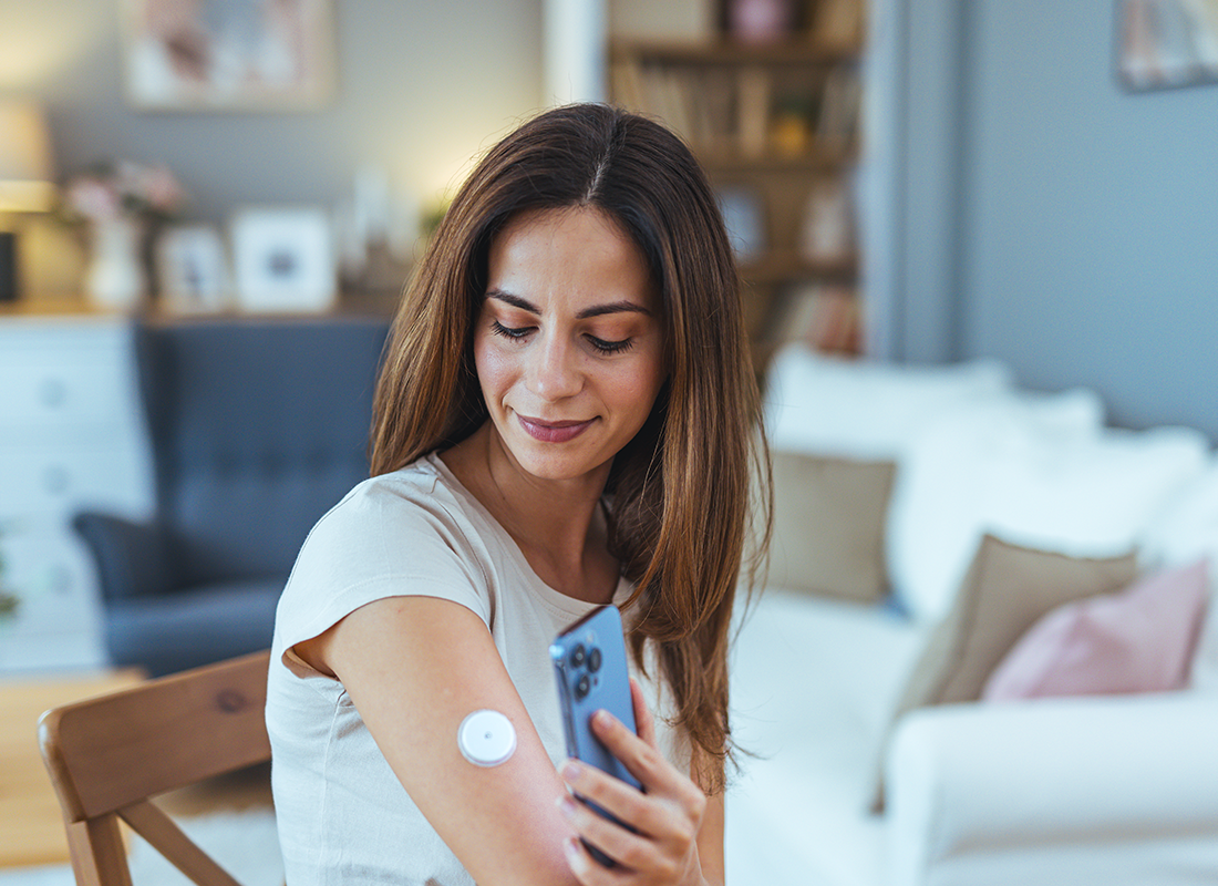Woman checking glucose sensor with smartphone